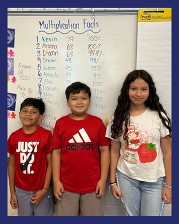 Three students stand in front of the leaderboard in Ms. Armstrong's classroom.