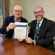 Scott York and Dave Jagels holding their signed partnership agreement together.