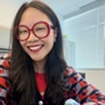 Ashlee Young headshot. Wearing red glasses and a printed blue and red sweater.