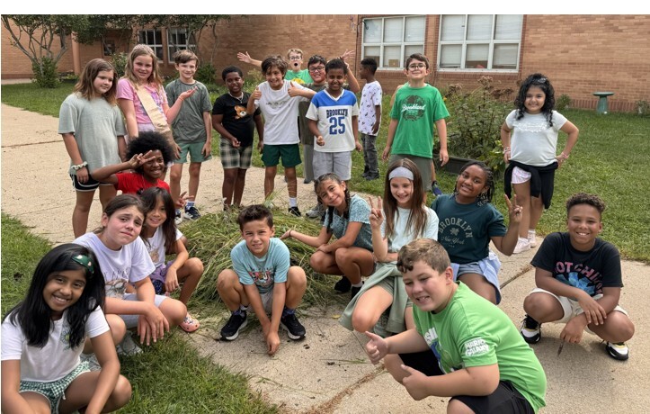 4th grade students showing off their weed pile in the garden