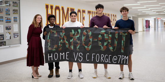 mrs matheny with students in front of a poster for Friday football