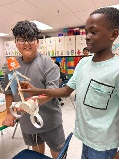 Two students test a structure they designed and built during STEAM class.