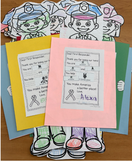 The image shows several colorful handmade cards and paper crafts honoring first responders.