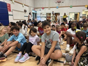 Students sitting at the schoolwide morning meeting