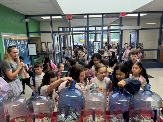 students placing coins in jars for penny wars