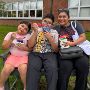 A mom and her two children smile while holding Kona Ice at Back-to-School Night.
