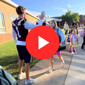 Football Player giving a high five to a girl getting off the bus