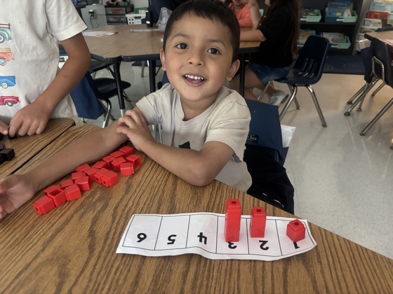 A boy is seen using red blocks to count