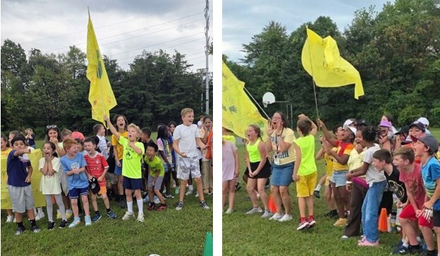 4th grade students wearing yellow holding their flag and cheering at the pep rally