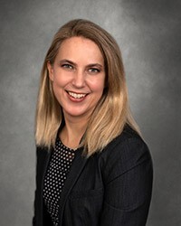 Headshot of Amy Miller, a smiling with shoulder-length blonde hair, wearing a dark blazer and patterned top.