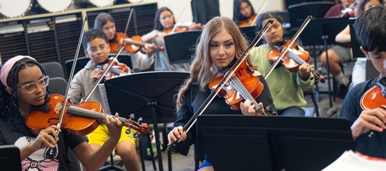 Students in Orchestra class playing violin