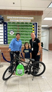 student standing with three adults behind black bicycle.