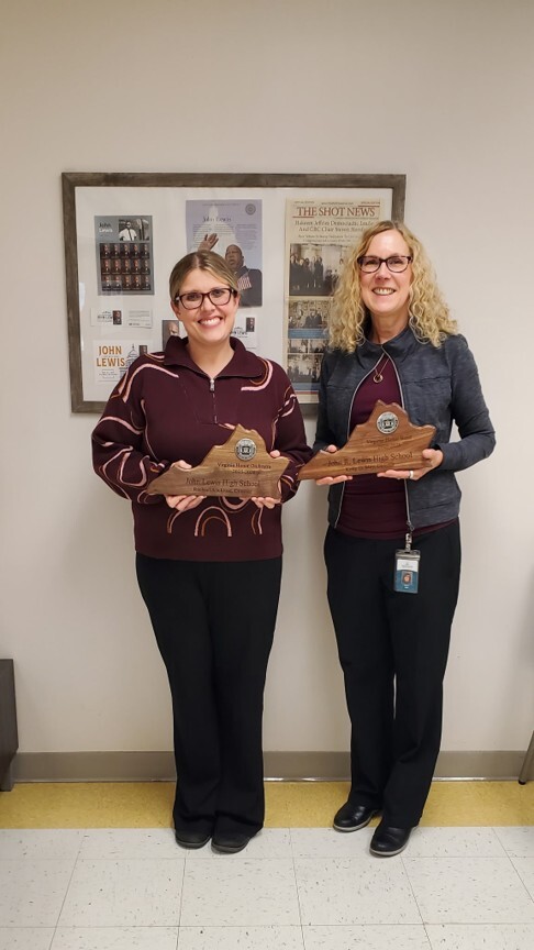 Image of two teachers both holding an award.