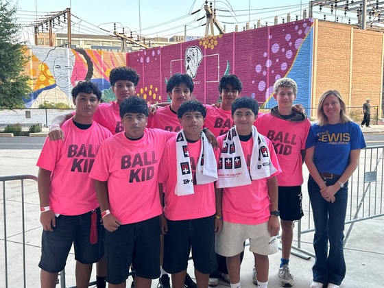Students in pink t-shirts that say Ball Kid standing along side a teacher 
