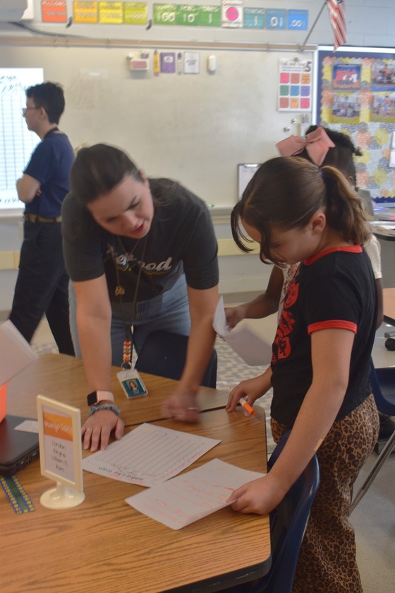 A picture of a teacher helping a student with a math activity