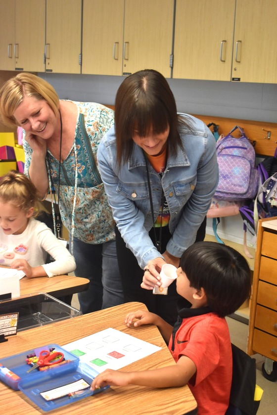 A picture of a teacher holding a cup to the student to learn about sense of smell