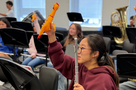 Student holding rubber chicken and flute