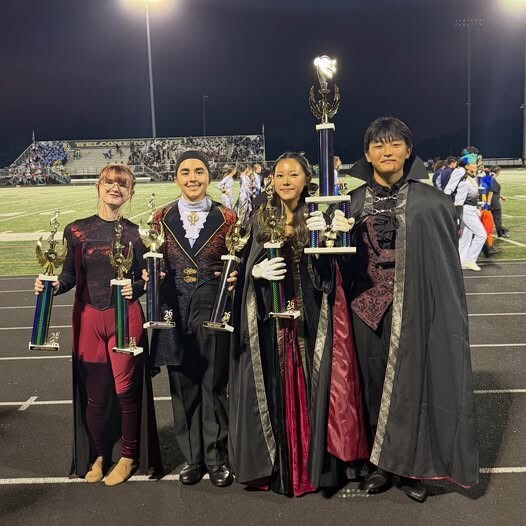 Students standing with trophies at a stadium