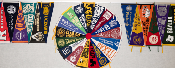 Various college pennants pinned up on a bulletin board 