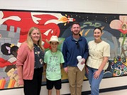 Picture of , Chris Kelley (Principal), Jackson (student), Kyle McDaniel (School board member), and Abby Holzinger (AP) in front of school mural