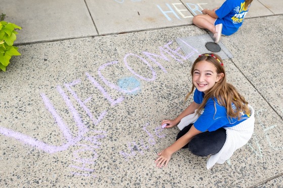 student coloring on the sidewalk with chalk