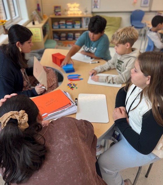 Students working with a teacher at a table