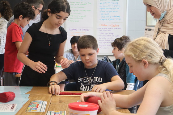 A boy and 2 girls presenting their work during the 6th grade parent invite