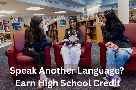 three students sitting in red chairs discussing books