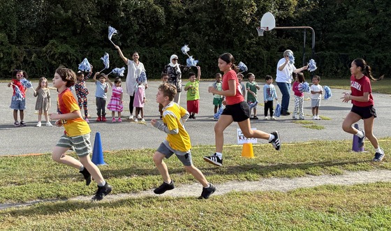 Preschool class cheering with pom poms for students running in the Fun Run