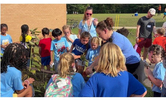 2nd graders watching their teachers release the monarch butterflies from their classroom into the school garden