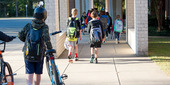 Students walking into school some with bikes and helmets