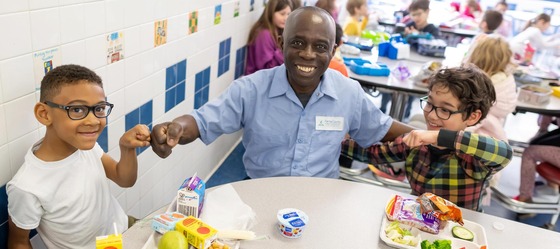 Amofa Agyekum, a custodian at Laurel Ridge Elementary sitting with a few students at lunch.