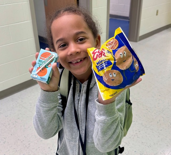 student in the hallway showing what they are going to eat for breakfast