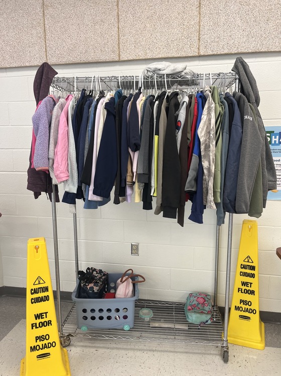 A clothing rack full of lost-and-found jackets and lunchboxes waiting to be claimed at Forestville Elementary.
