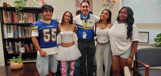 Three students with a teacher dressed in customs for spirit week