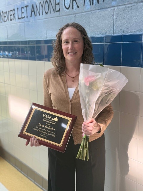 Teacher holding pink flowers and a plaque