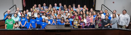 School Board members, Des Colores ensemble and directors, accompanists, teachers in front of the dais with Hispanic Heritage Month proclamation