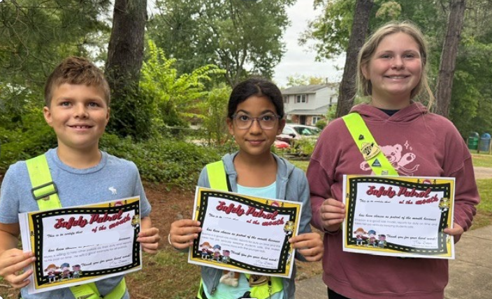 Three safety patrol students holding Safety Patrol of the Month awards.   