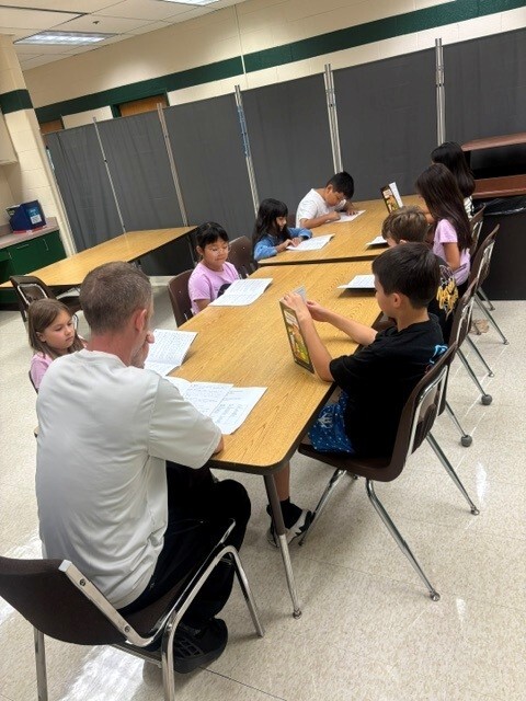 Mr. Tyler with students doing readers theatre with 3rd graders.