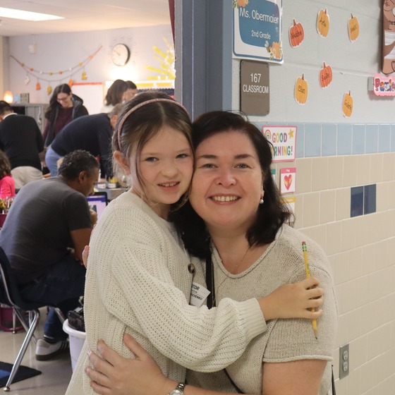 A 2nd grader hugging her mother outside her 2nd grade classroom