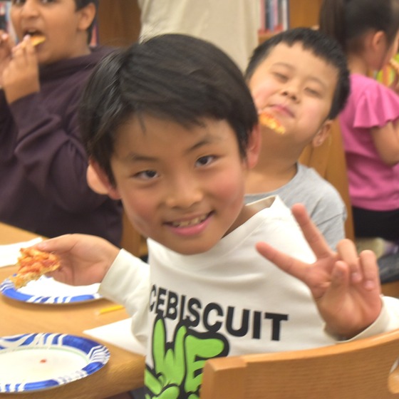 A student giving a piece sign at the CARE Pizza luncheon