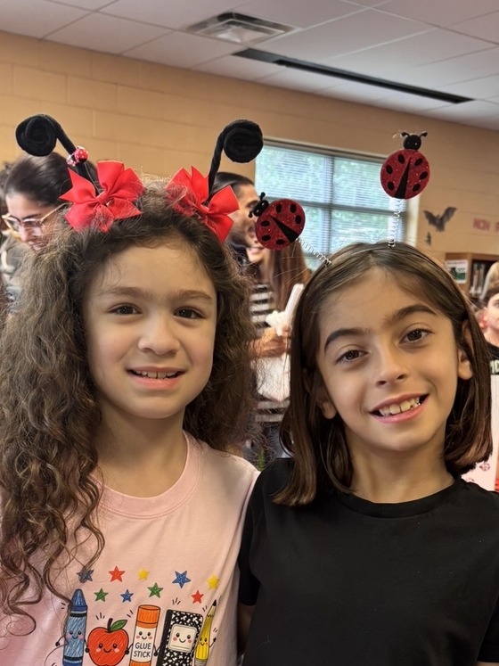Two smiling students wearing ladybug antenna headbands celebrating our 3rd grade Ladybug Museum.