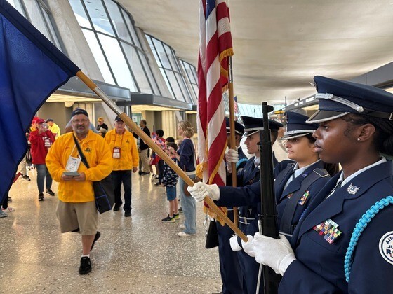 AFJROTC Color Guard in dress uniform holding flags and a ceremonial rifle to welcome veterans inside Washington Dulles International Airport