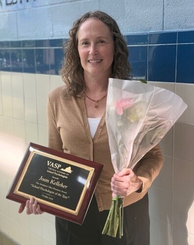 oan Kelleher holding a bouquet of flowers and a plaque after being named "School Psychologist of the Year" by Virginia Academy of School Psychologists