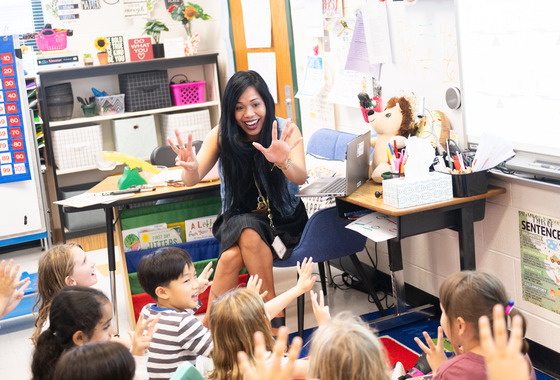 A teacher excitedly displays 8 fingers for young students.