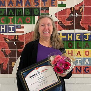 A teacher holds a certificate and flowers