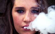 A young woman with smoke from an E-cigarette coming out of her mouth