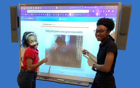 Two students working on a smartboard for a digital citizenship presentation