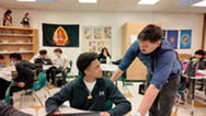 teacher helping student with schoolwork at desk