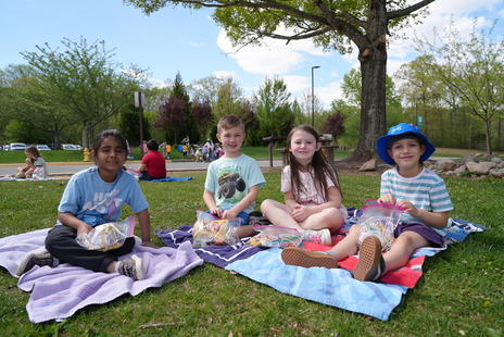 four students sitting outside on picnic blankets, smiling